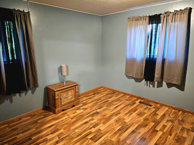 spare room with a textured ceiling and hardwood / wood-style floors