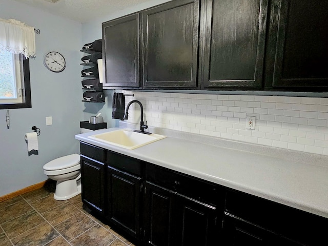 bathroom with vanity, toilet, and tasteful backsplash