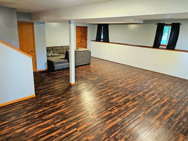 basement featuring a textured ceiling and dark hardwood / wood-style floors