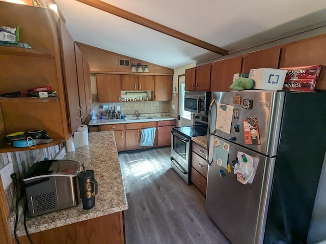 kitchen with appliances with stainless steel finishes, decorative backsplash, wood-type flooring, lofted ceiling with beams, and sink