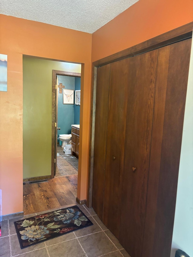 corridor featuring a textured ceiling and dark hardwood / wood-style flooring