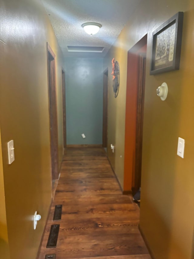 hallway with a textured ceiling and dark wood-type flooring