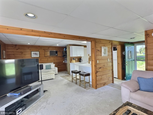 living room featuring recessed lighting, light carpet, a paneled ceiling, and wooden walls