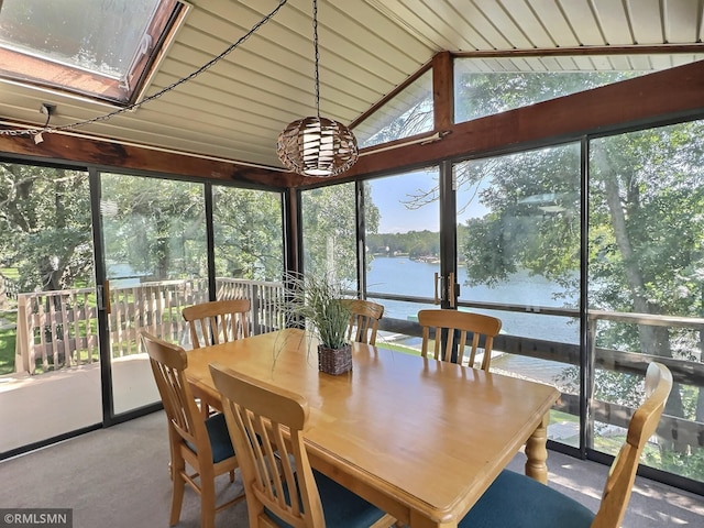 sunroom featuring a water view and vaulted ceiling with skylight