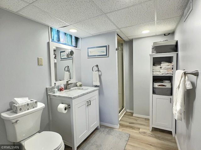 bathroom featuring vanity, wood-type flooring, a drop ceiling, walk in shower, and toilet