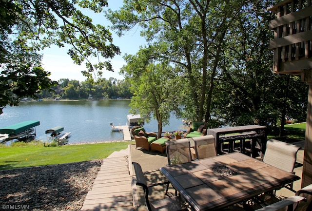 exterior space with outdoor dining space, a water view, and a yard