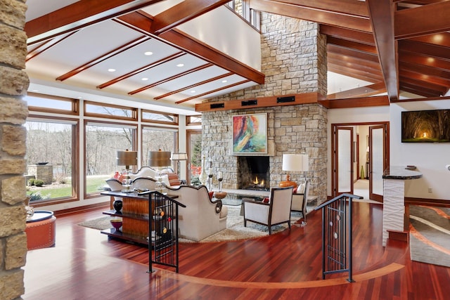 living room featuring wood-type flooring, a stone fireplace, and lofted ceiling with beams