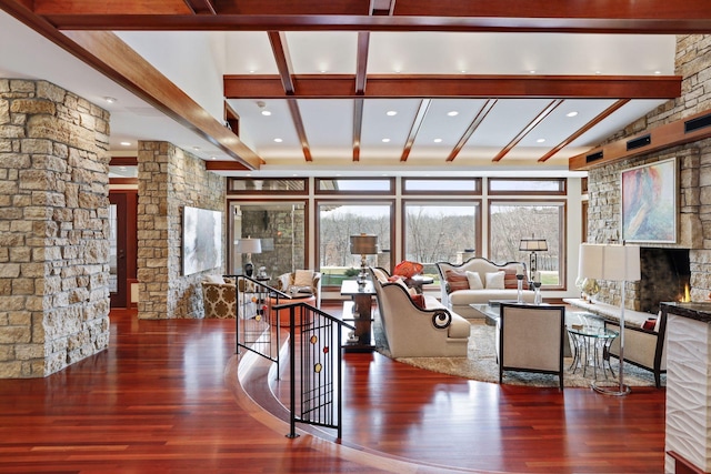 interior space featuring vaulted ceiling with beams, hardwood / wood-style floors, and a stone fireplace