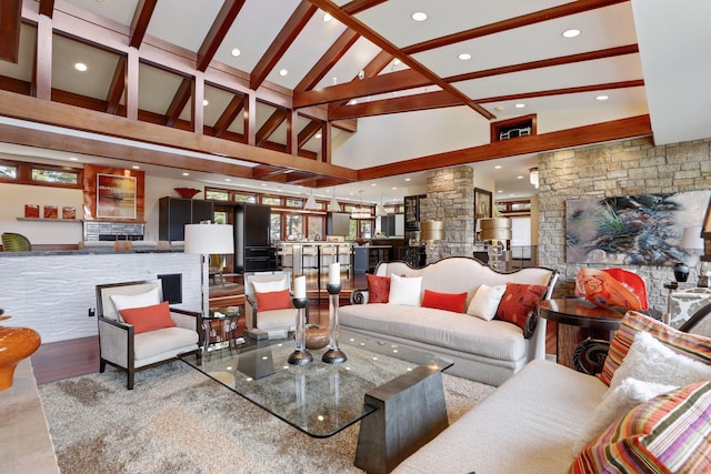 living room with high vaulted ceiling, beam ceiling, hardwood / wood-style floors, and a stone fireplace