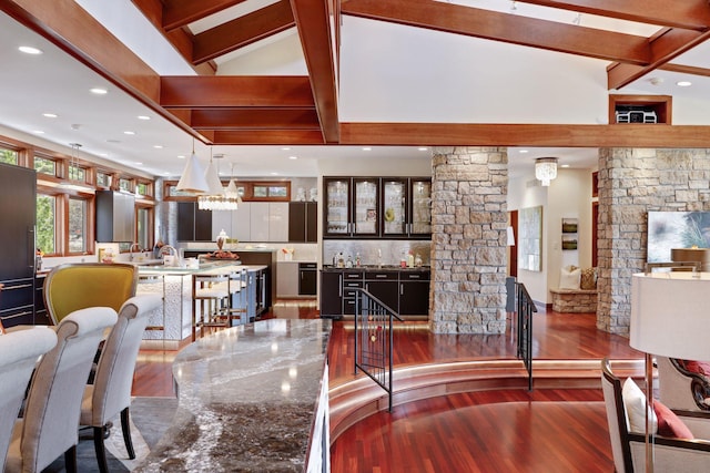 living room with vaulted ceiling with beams, bar, dark wood-type flooring, and ornate columns