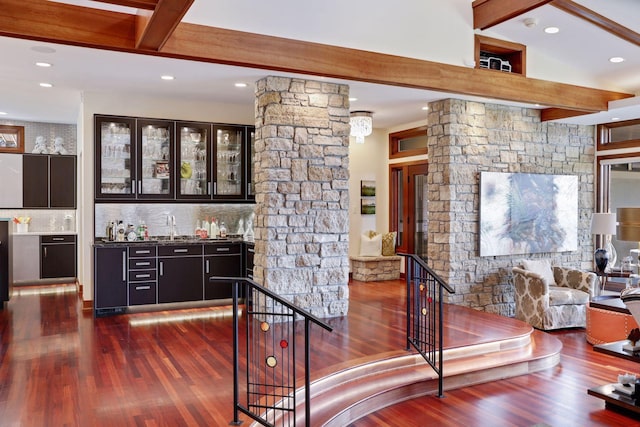 interior space featuring beam ceiling, decorative columns, dark wood-type flooring, and tasteful backsplash