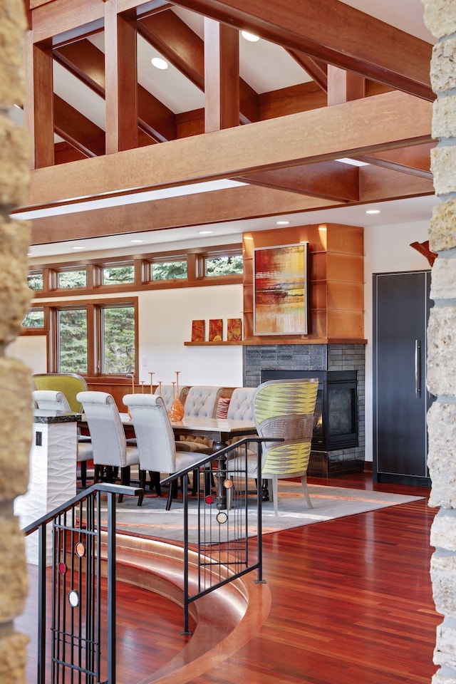 dining room with a fireplace, beam ceiling, and hardwood / wood-style floors