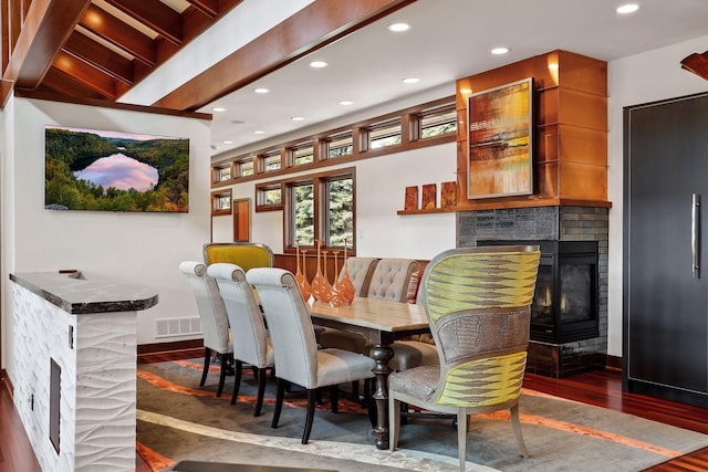 dining room featuring a multi sided fireplace and dark hardwood / wood-style flooring