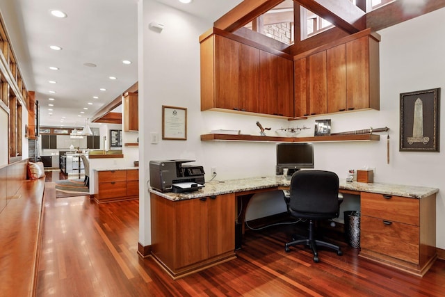 office with a towering ceiling, built in desk, and dark wood-type flooring