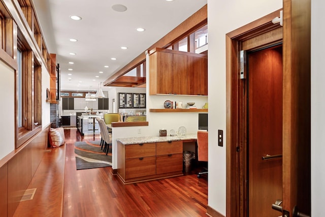 kitchen featuring light stone countertops, built in desk, dark hardwood / wood-style floors, and decorative light fixtures