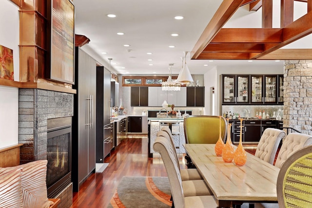 dining space with a stone fireplace, bar area, and dark hardwood / wood-style floors