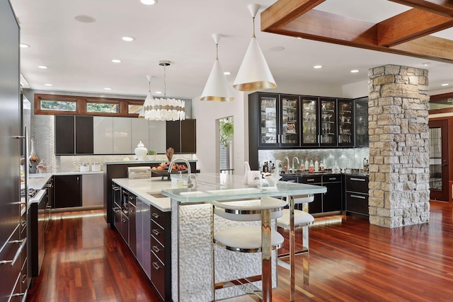 kitchen featuring sink, tasteful backsplash, a kitchen bar, ornate columns, and dark hardwood / wood-style flooring