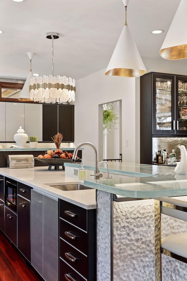 bar with dark hardwood / wood-style flooring, backsplash, decorative light fixtures, and sink