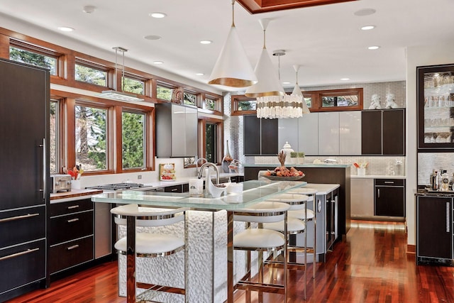 kitchen featuring pendant lighting, a center island, dark hardwood / wood-style floors, a breakfast bar area, and decorative backsplash