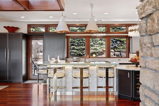 bar with high quality fridge, hanging light fixtures, dark hardwood / wood-style flooring, and a healthy amount of sunlight