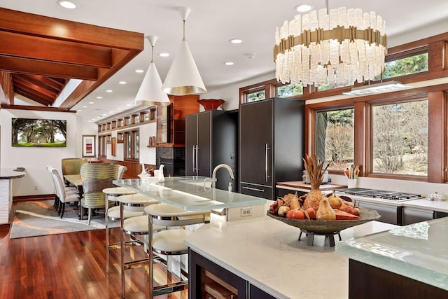 kitchen featuring a notable chandelier, stainless steel appliances, hanging light fixtures, and dark wood-type flooring