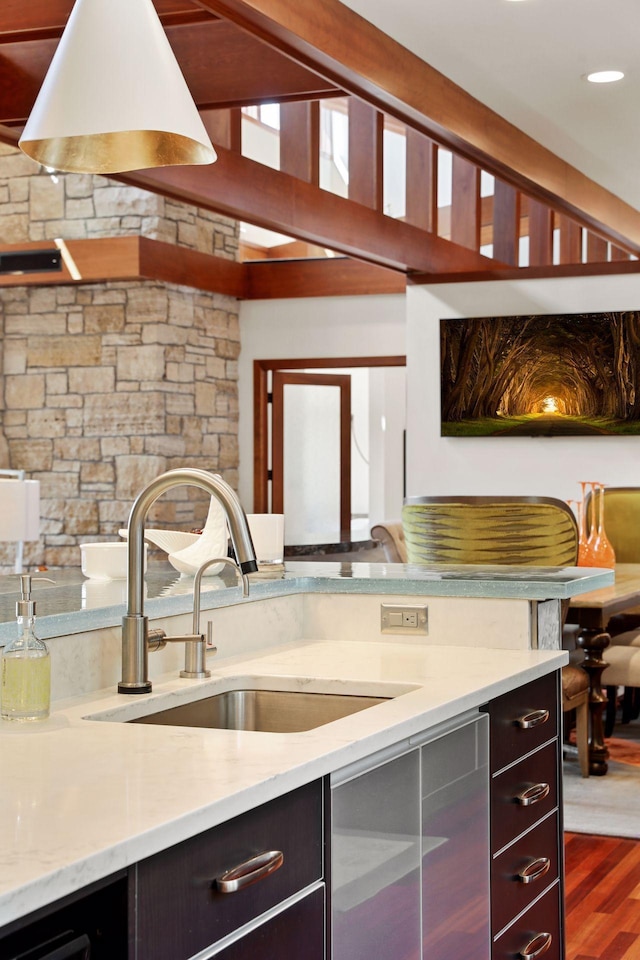 kitchen with light stone countertops, dark wood-type flooring, and sink