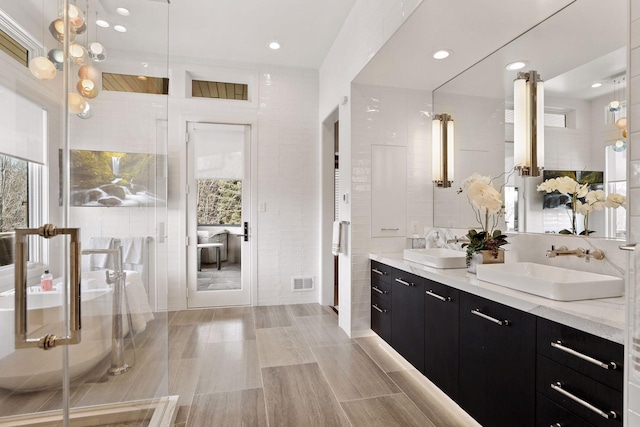 bathroom with tile walls, a shower with shower door, and vanity