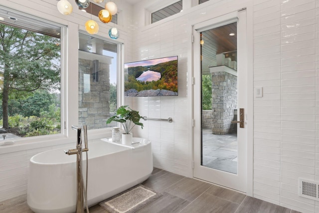 bathroom featuring a tub to relax in and tile walls