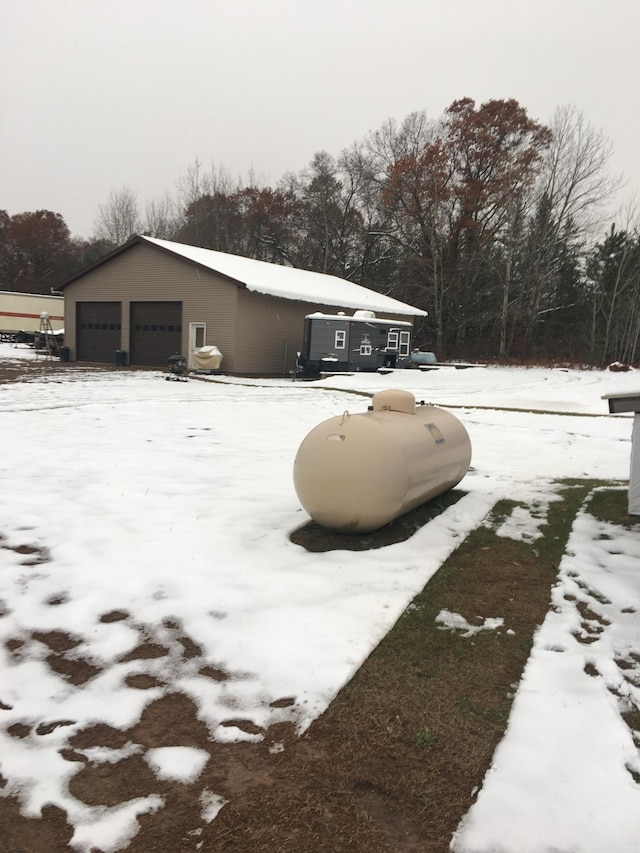 snow covered property with a garage and an outbuilding