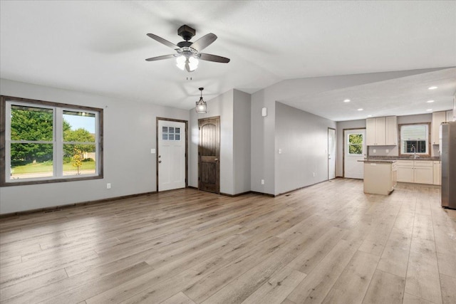 unfurnished living room featuring ceiling fan, lofted ceiling, and light hardwood / wood-style floors