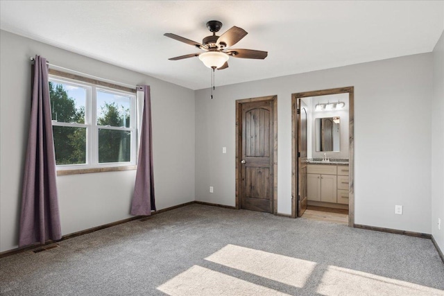 unfurnished bedroom featuring ceiling fan, ensuite bath, sink, and light carpet