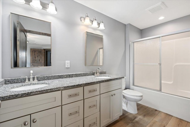 full bathroom featuring vanity, wood-type flooring, shower / bath combination with glass door, and toilet