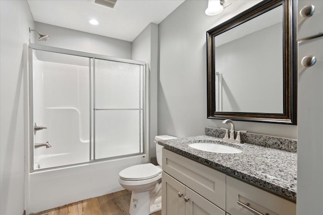 full bathroom featuring vanity, combined bath / shower with glass door, hardwood / wood-style floors, and toilet