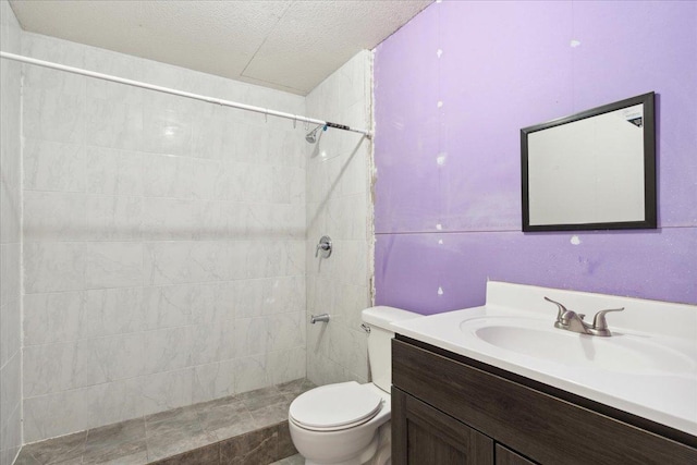 bathroom with vanity, tiled shower, a textured ceiling, and toilet