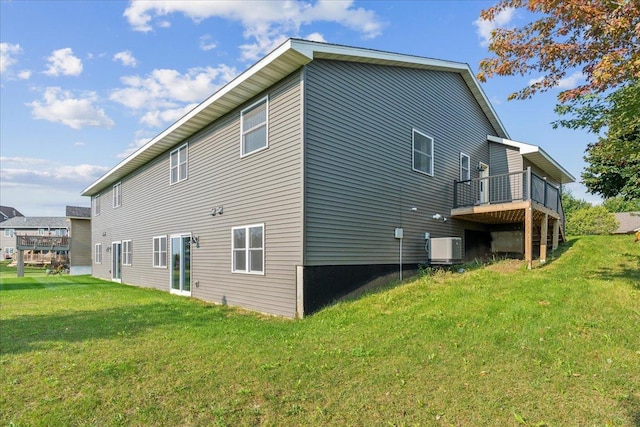 rear view of property with central AC unit and a lawn