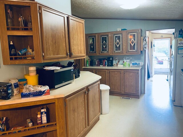 kitchen with stainless steel appliances, a textured ceiling, and lofted ceiling