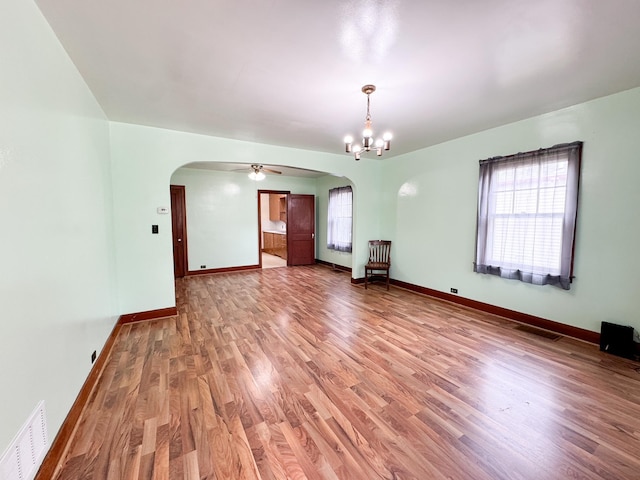 empty room with ceiling fan with notable chandelier and hardwood / wood-style floors