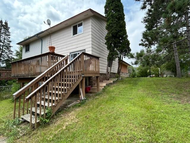 rear view of house with a deck and a lawn