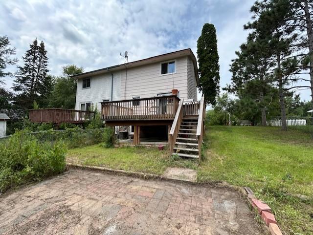 rear view of house with a wooden deck and a yard