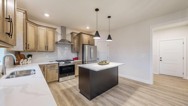 kitchen with light hardwood / wood-style floors, a center island, sink, wall chimney range hood, and appliances with stainless steel finishes