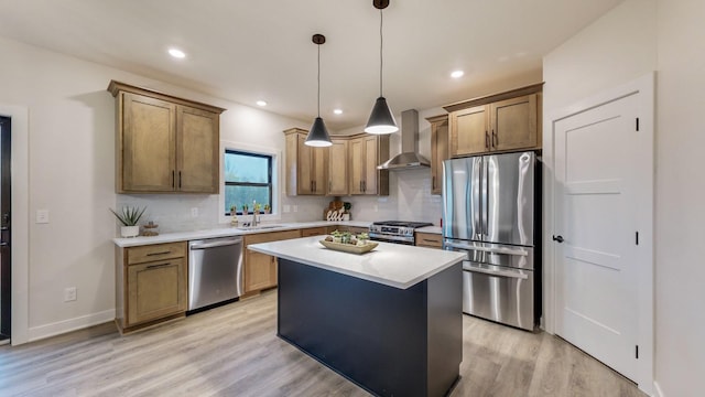 kitchen with light hardwood / wood-style floors, appliances with stainless steel finishes, hanging light fixtures, a center island, and wall chimney range hood