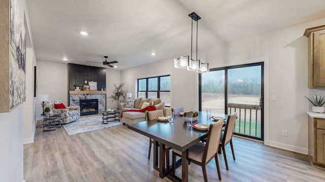 dining space with ceiling fan, light hardwood / wood-style floors, and a fireplace