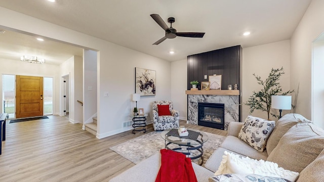 living room featuring ceiling fan, a high end fireplace, and light hardwood / wood-style floors