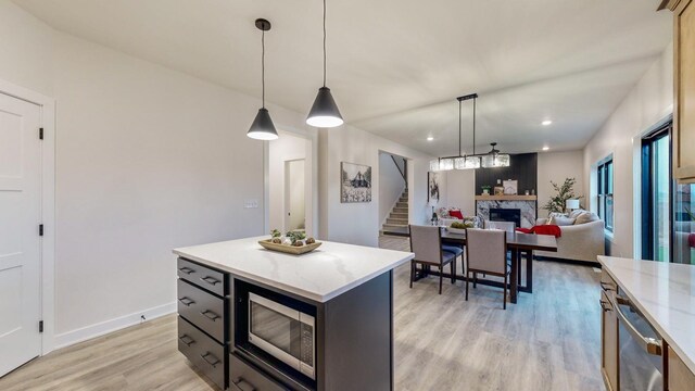 1701 20th Ave Circle NE, Kasson, MN 55944 - kitchen with stainless steel microwave, a fireplace, light wood-type flooring, recessed lighting, and hanging light fixtures