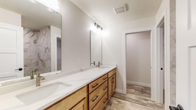1701 20th Ave Circle NE, Kasson, MN 55944 - full bath featuring double vanity, wood finished floors, baseboards, and a shower