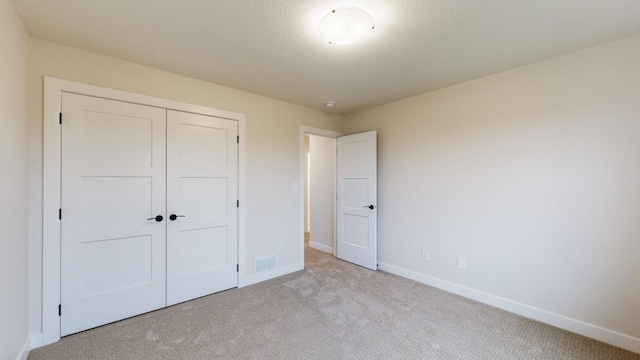 unfurnished bedroom featuring light carpet and a closet