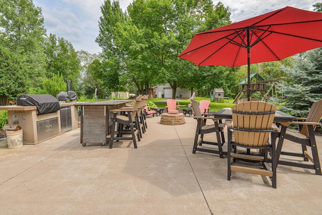 view of patio / terrace featuring grilling area, a fire pit, an outdoor kitchen, and a storage unit