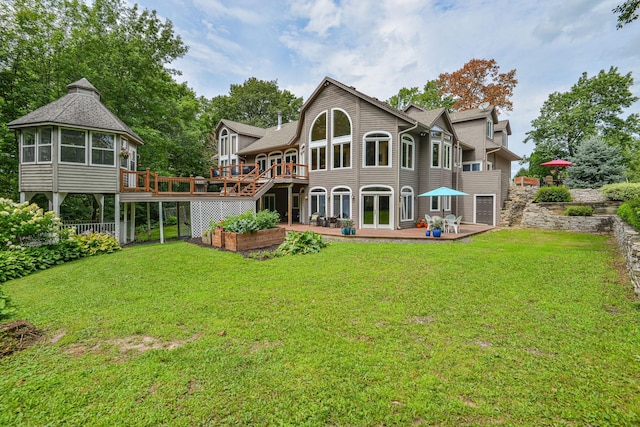 rear view of house with a yard, a wooden deck, and a patio area