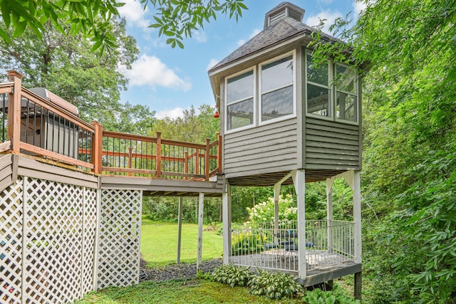 view of side of property with a sunroom, a lawn, and a wooden deck