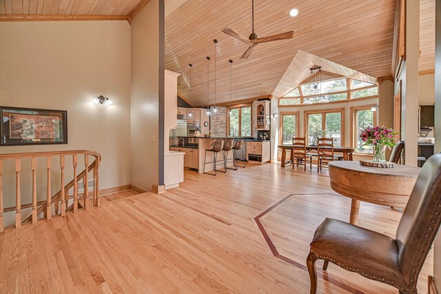 living room with wooden ceiling, high vaulted ceiling, a wealth of natural light, and light hardwood / wood-style floors